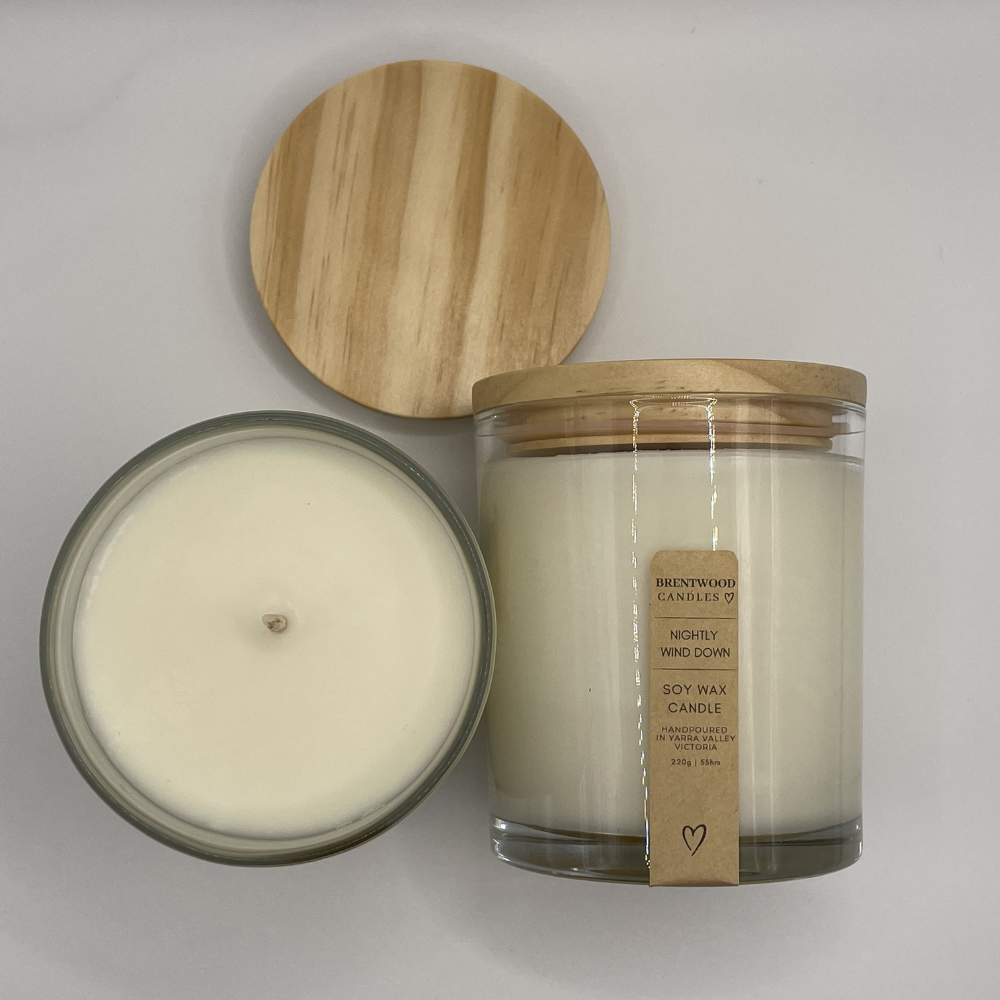 Candle with wooden lid and label on a grey background